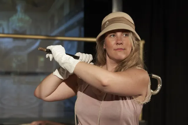 Jordan Baker mit Golfschläger und Cloche-Hut